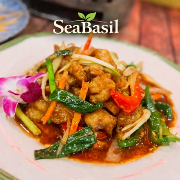 Seabasil Thai & Seafood's crispy chicken stir-fry with vegetables and a purple orchid garnish.