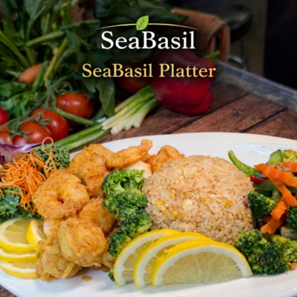 A SeaBasil Platter with fried shrimp, fried rice, broccoli, carrots, and lemon slices.