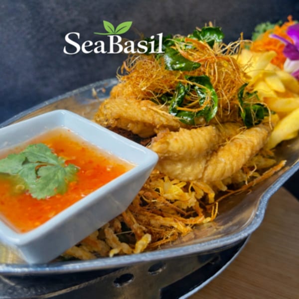 Crispy fried Thai chicken wings with sweet chili sauce, garnished with herbs and vegetables.